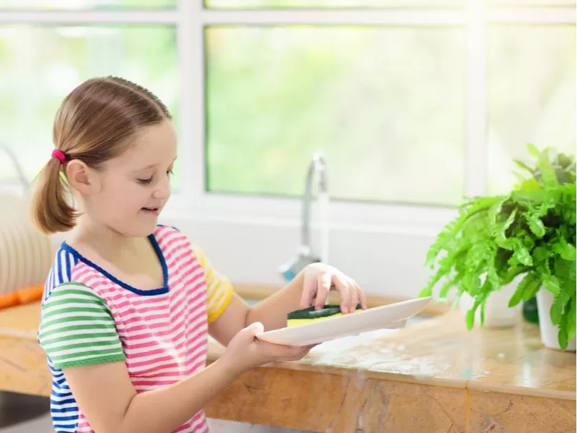 girl washing plate with sponge