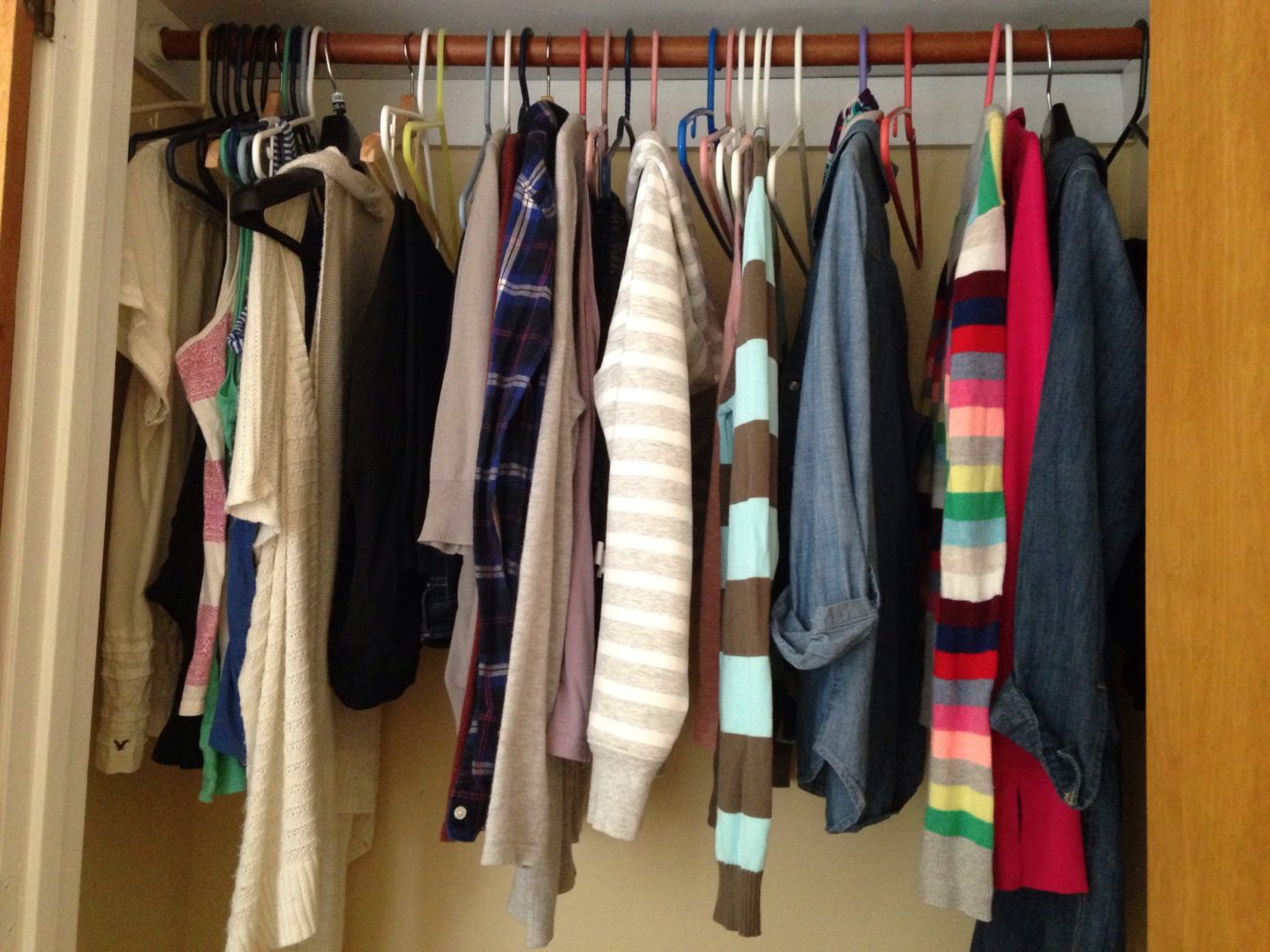 closet with capsule wardrobe hanging on hangers, sweatshirts and sweaters, tank tops