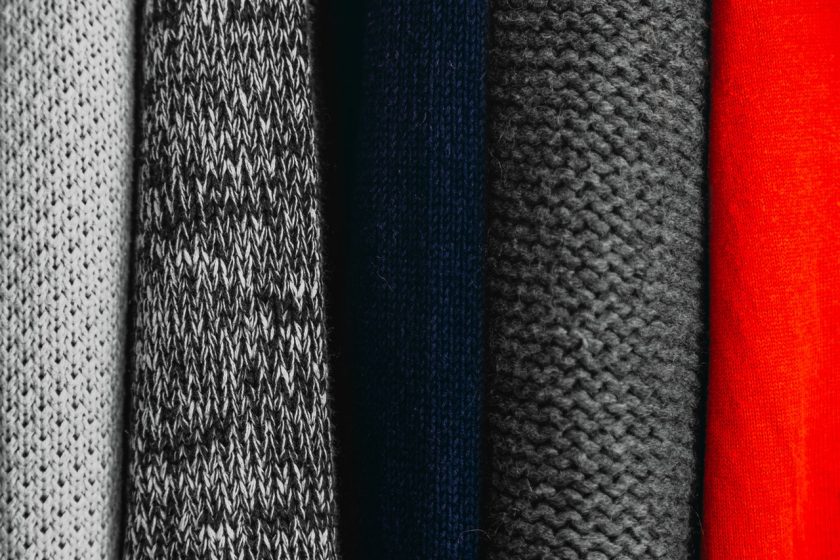 close up of sweaters folded the marie kondo way, grays, blacks and red
