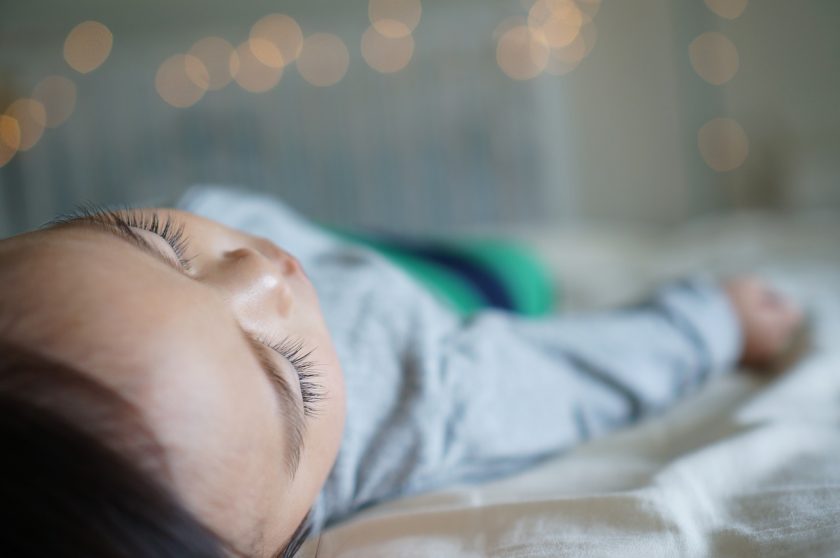 sleeping young girl on bed with twinkle lights in background