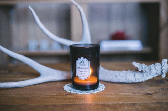 lit candle in amber glass jar and white antler on wooden table