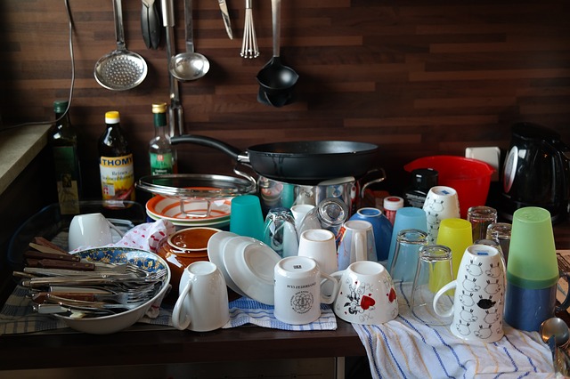 kitchen counter covered with clean dishes, mugs, plates, silverware, pots and pans