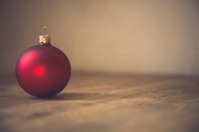 single red ball Christmas ornament on wooden countertop