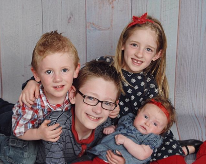 four siblings posing family photo, ranging from older child to baby