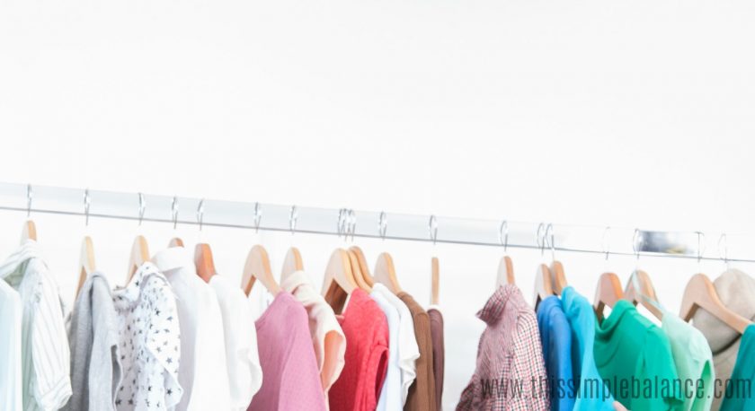 clothing rack with kids' clothes on hangers organized by color