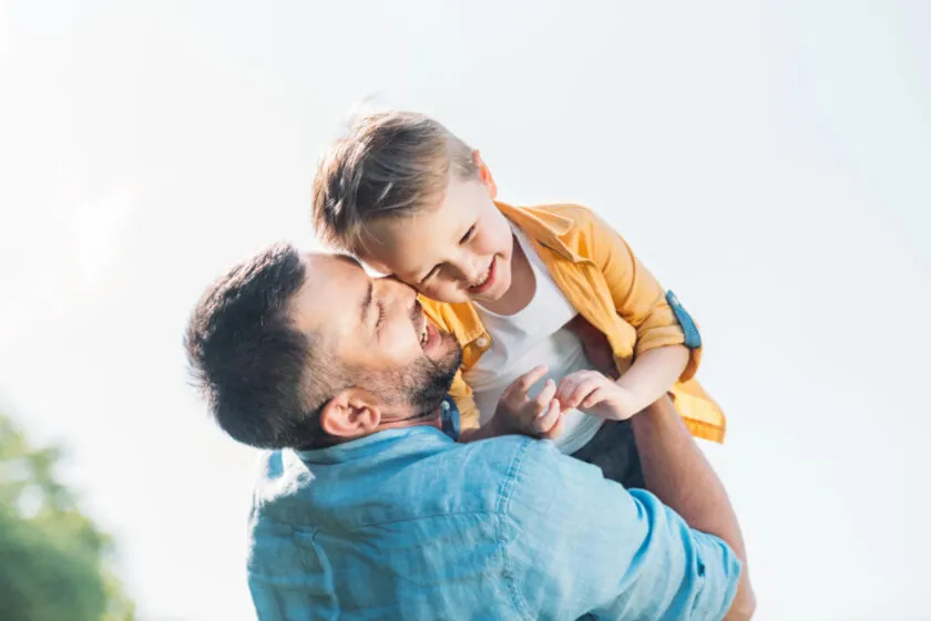happy dad smiling and holding up his happy young child.