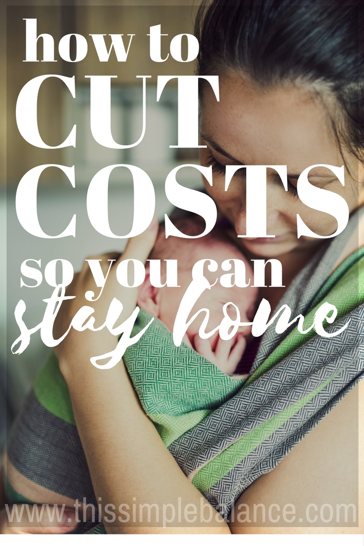 stay at home mom holding baby close in baby wrap, with text overlay "how to cut costs so you can stay home"