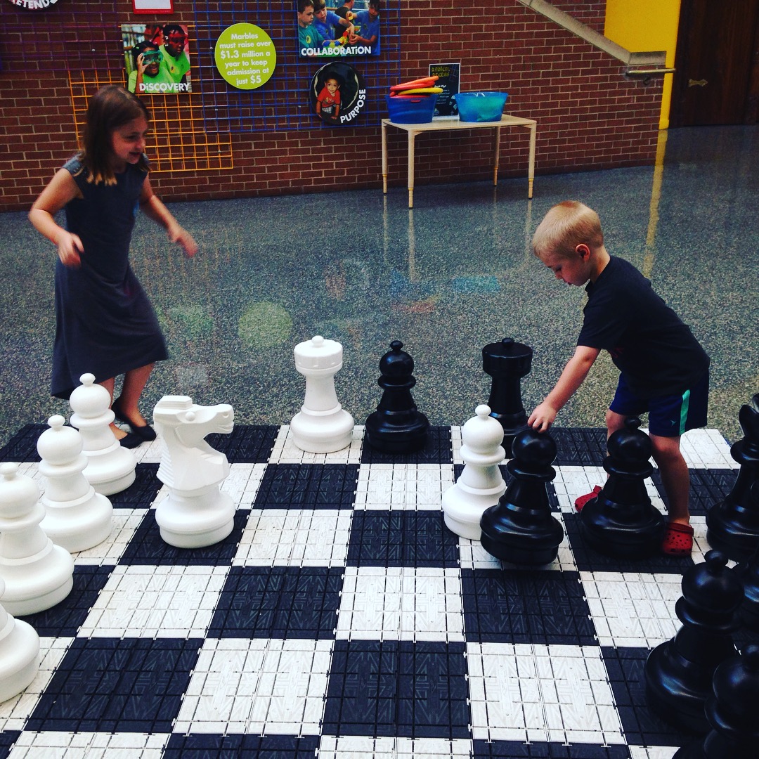 brother and sister playing life-sized chess at the local children's museum