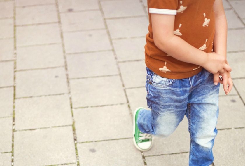 little boy in jeans running on concrete block surface