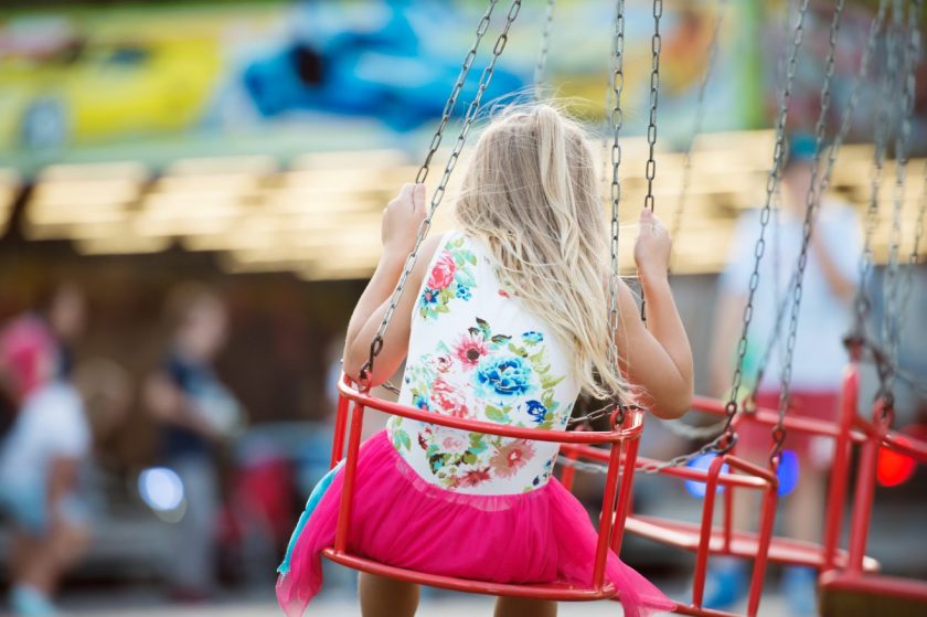 young girl riding amusement park swing type ride