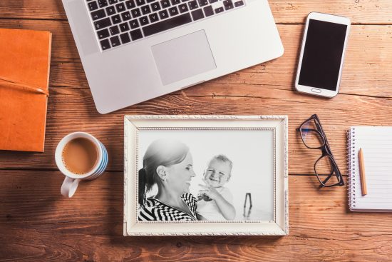framed picture of homeschool mom with child on desk with laptop , mug, glasses and phone