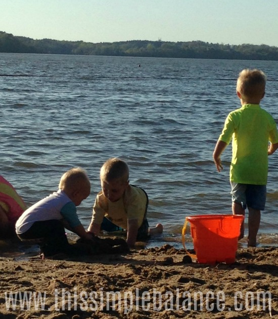 three young brothers playing at the lake in the sand