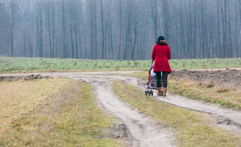 homeschool mom pushing stroller down a country dirt road