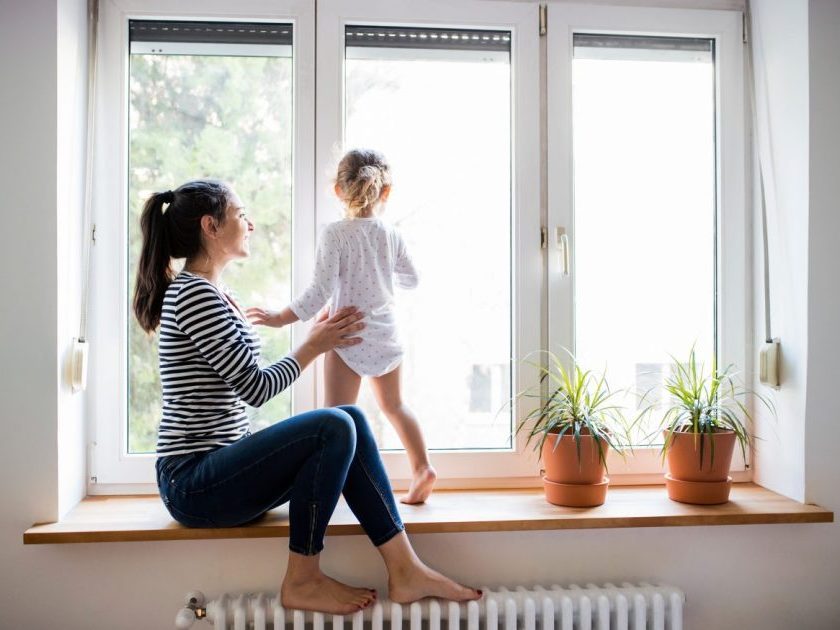 minimalist mom sitting on windowsill with toddler who is looking out the window