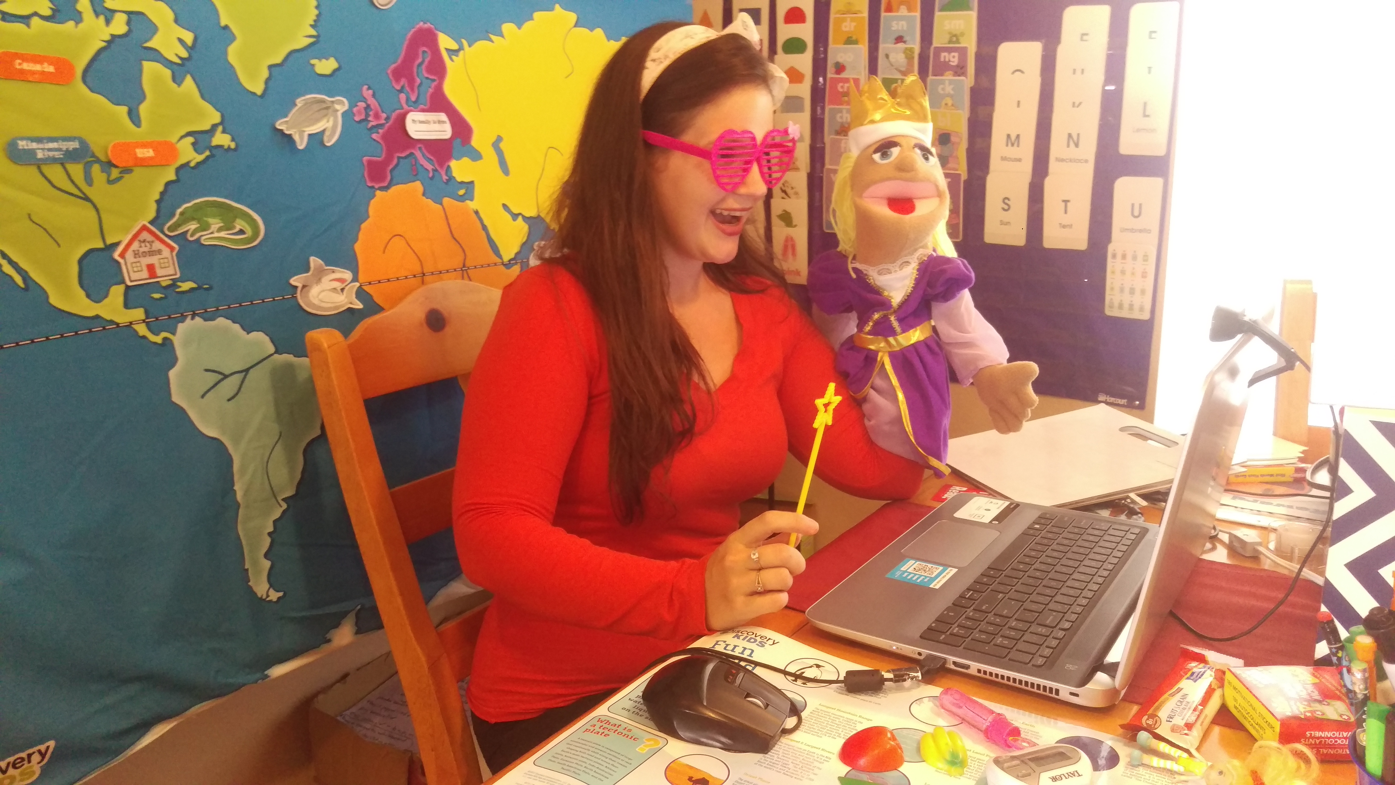 VIPKID teacher with heart glasses and a puppet, teaching ESL through her laptop