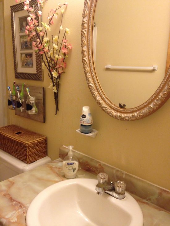 bathroom sink and mirror, with clear counters except for soap, flowers and photos and toothbrushes on wall