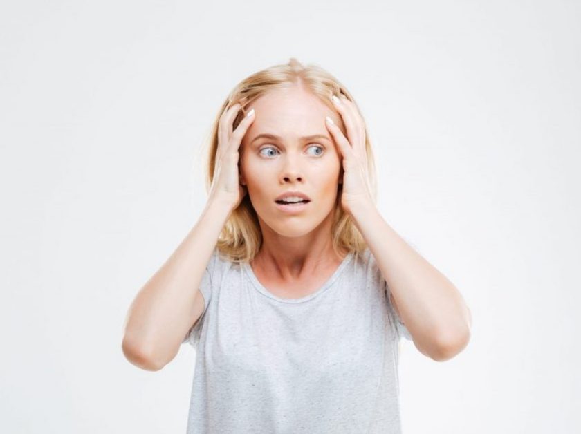 woman holding head in her hands looking overwhelmed
