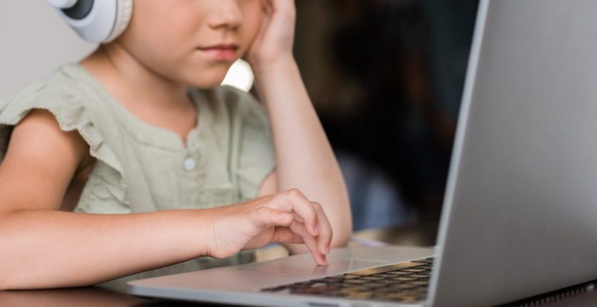 child doing homeschool french program on computer with headphones