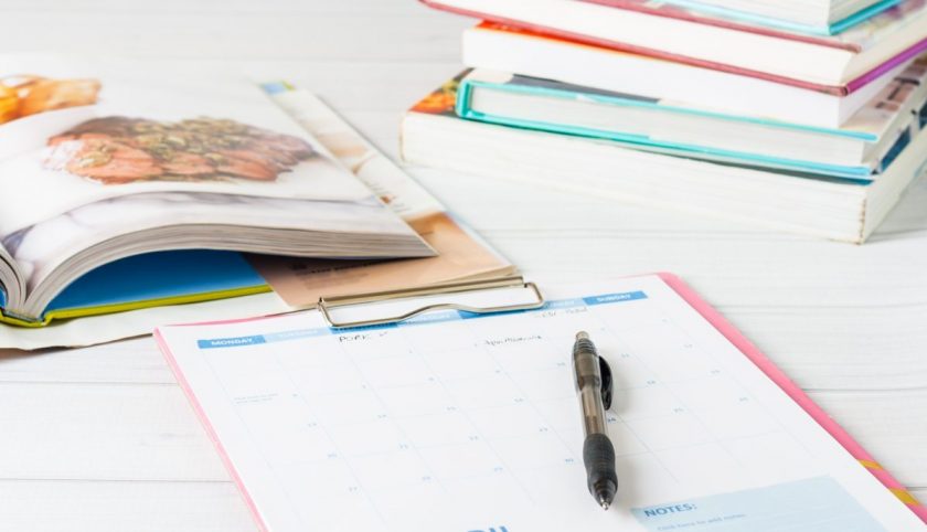 minimalist meal planning printable and pen with cookbooks spread out on table