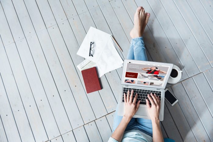 woman sitting on deck, legs spread out with laptop on her lap, working