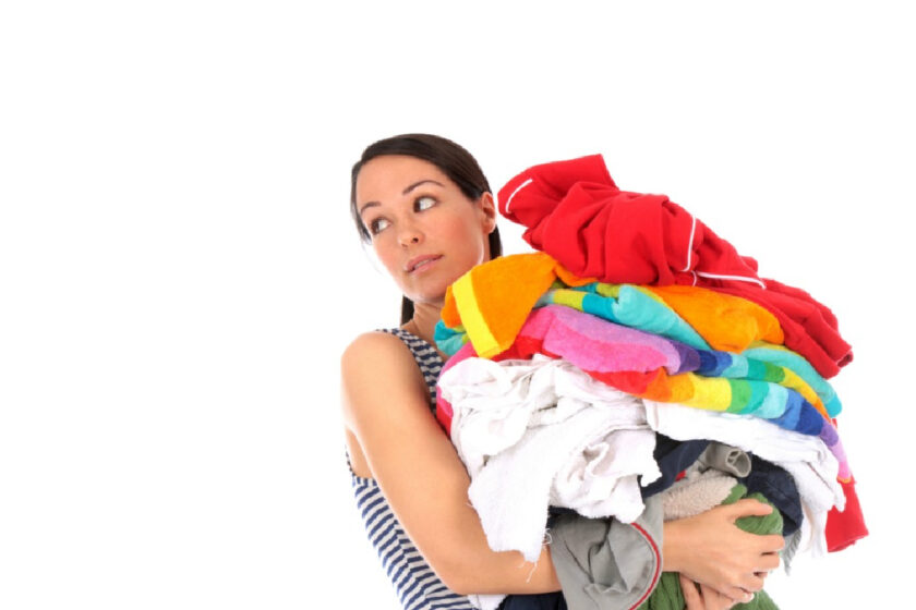 woman holding tons of clothes rolling her eyes, attempting to declutter
