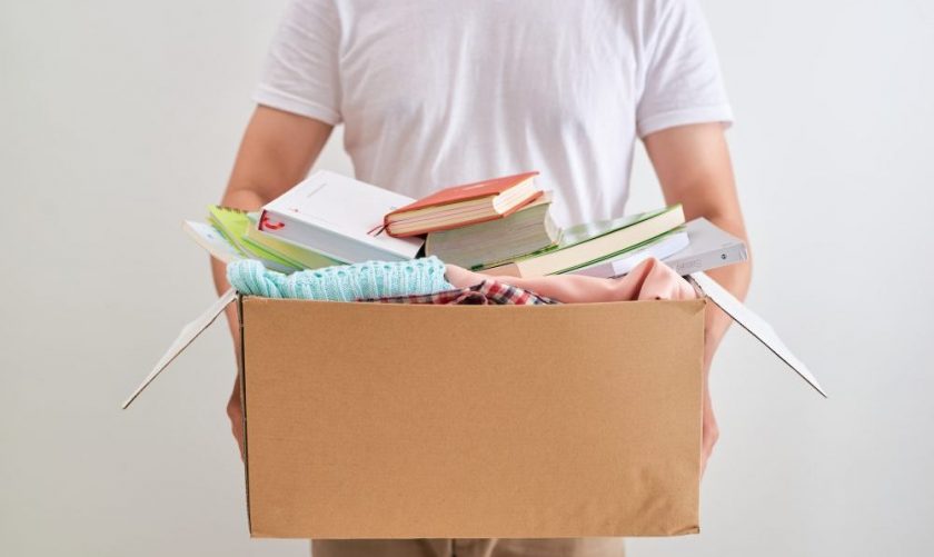man in white t-shirt holding cardboard box of stuff to get rid of