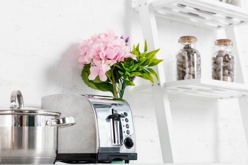 decluttered kitchen with toaster, stock post and vase of flowers and simple white shelf with jars