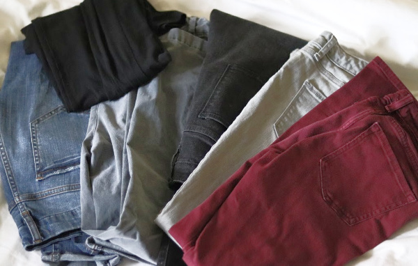 gray, blue, black and burgundy jeans with black leggings on white bedspread