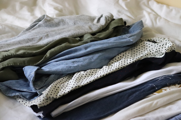 blue, gray and white fall capsule wardrobe tops, displayed on white bedspread