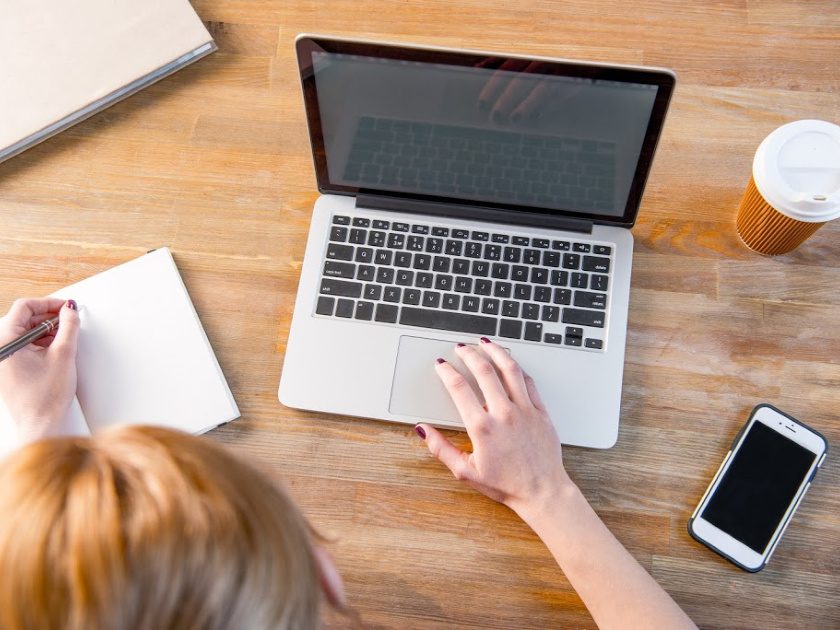 homeschool mom working on a computer, notebook and phone on desk