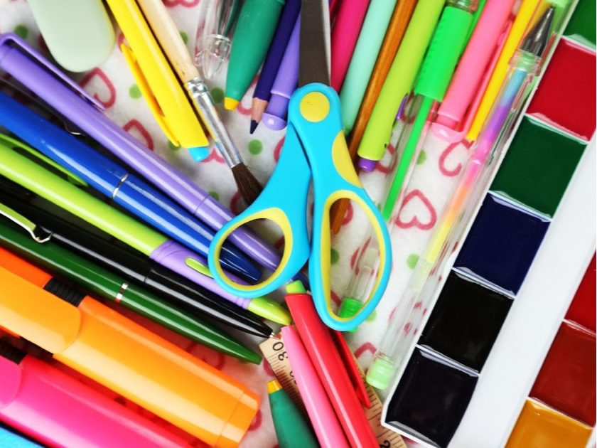 colorful homeschool supplies on table, including scissors, markers, pens and watercolors