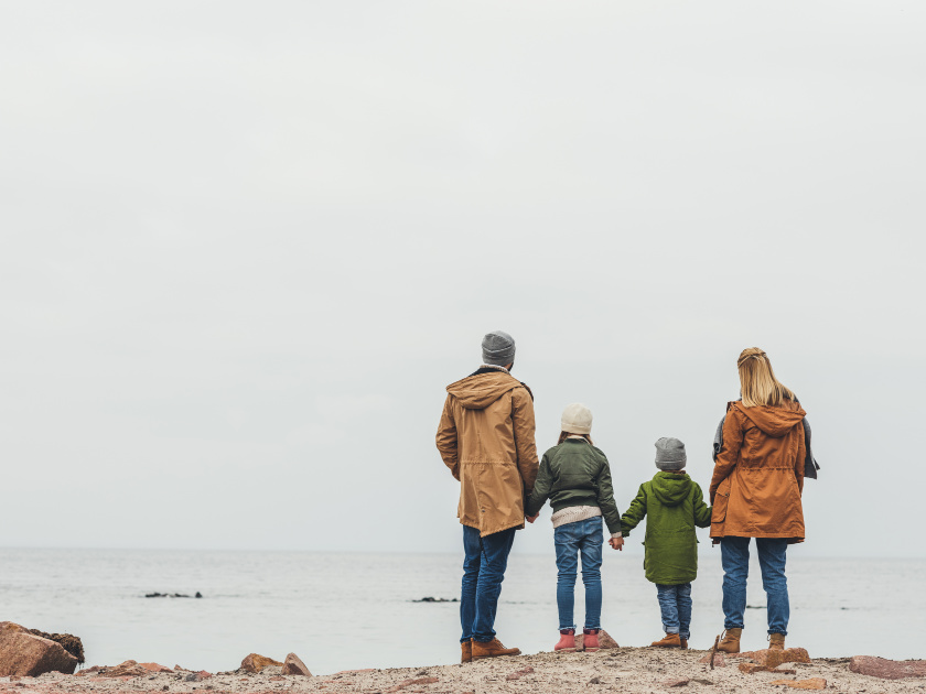 minimalist family with two kids dressed warmly at the ocean in winter