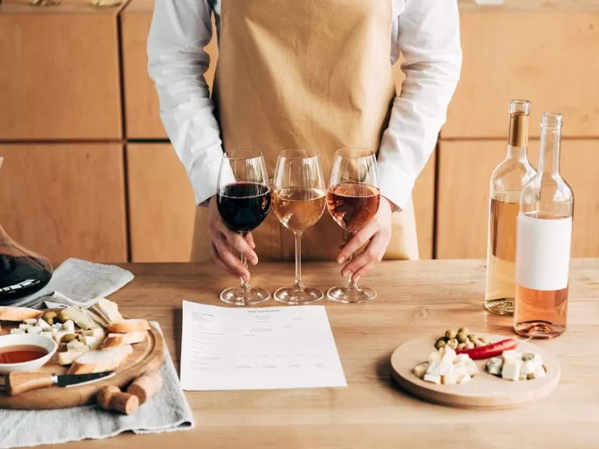 man in brown apron with wine bottles, glasses and charcuterie boards