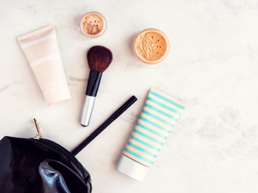 minimalist makeup collection and black makeup bag spread out on counter