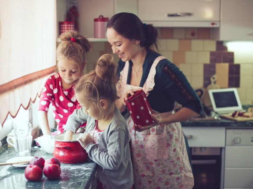 homeschool mom in apron baking with two young daughters