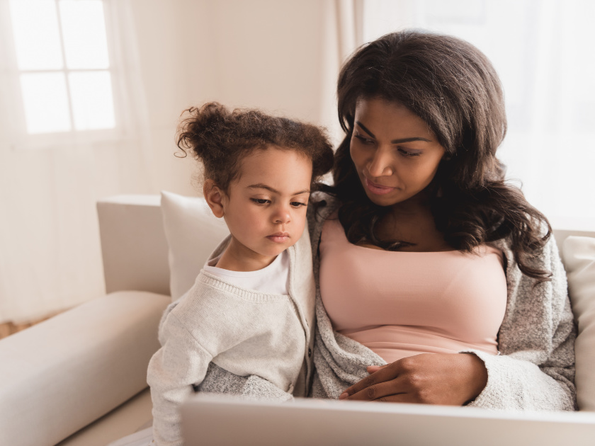 mom sitting on couch with young daughter, wondering, "Should I homeschool my child?"