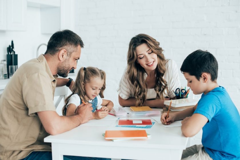 homeschool mom, dad and two kids sitting around table doing homeschool work