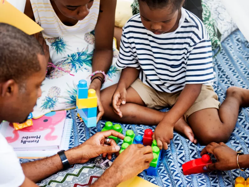 family sitting on blanket building with mega blocks