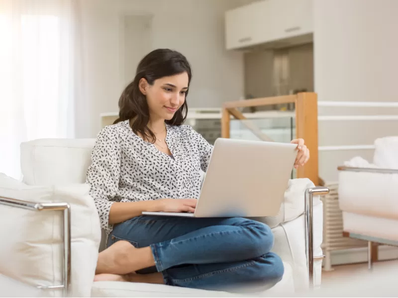 mom sitting in armchair with laptop, researching homeschooling