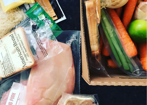 meal kit contents spread on counter including uncooked chicken breast and various vegetables