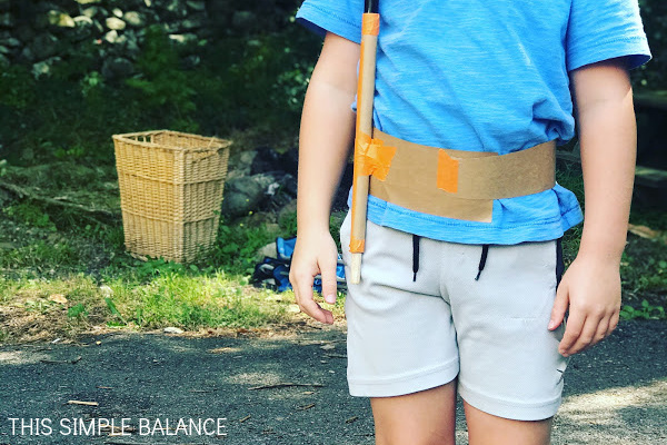 boy modeling a belt he made from cardboard