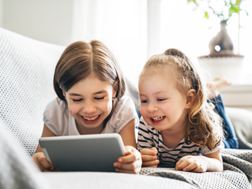 two young sisters who have unlimited screen time playing a game together on a tablet