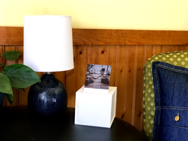 black side table with authenticity quote calendar and blue lamp on it