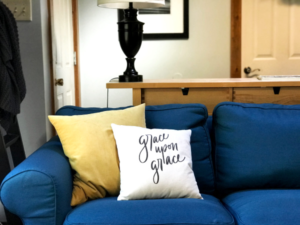 blue couch with yellow and canvas throw pillow with words "grace upon grace"