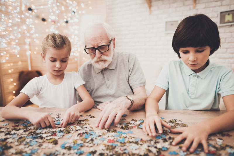 grandpa and children doing a puzzle at Christmas