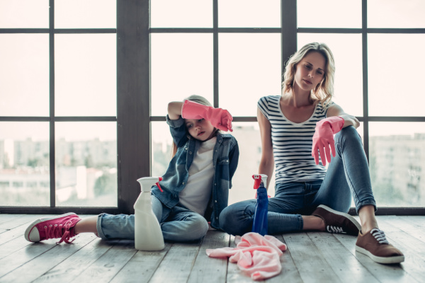 mom and daughter sitting with backs to windows, exhausted from cleaning