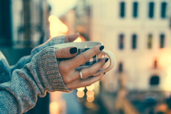 woman's hands holding a black and white checkered coffee mug with city in the background