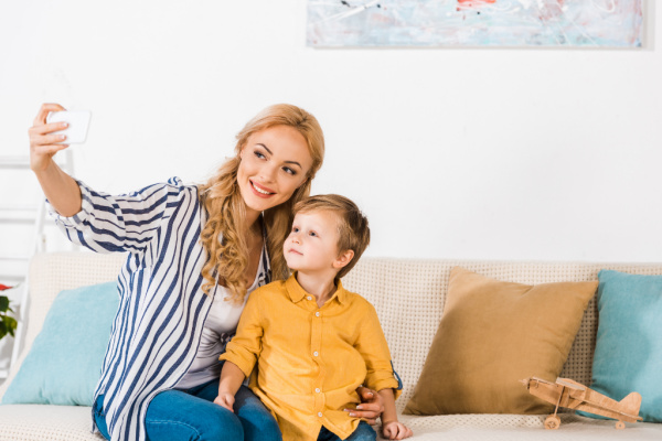 mom and son posing for selfie on tan sofa