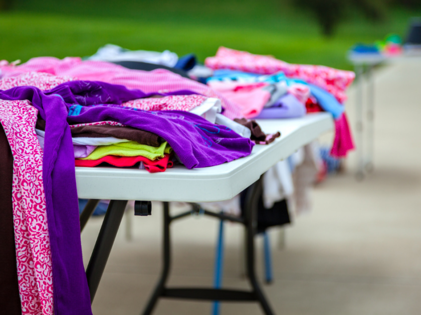 white folding tables with clothes set out for a yard sale