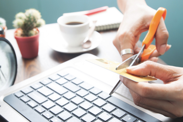 hands cutting credit card with scissors over laptop keyboard